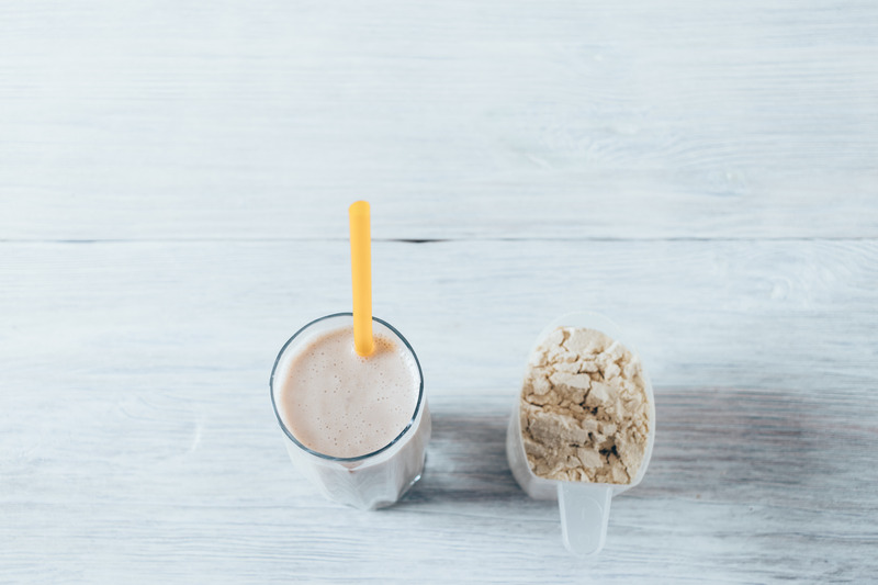 Whey protein shake in glass with straw